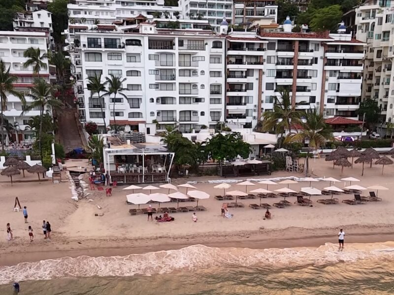 Los Muertos beach in Zona Rom&aacute;ntica, Puerto Vallarta, with beach umbrellas and condo buildings behind