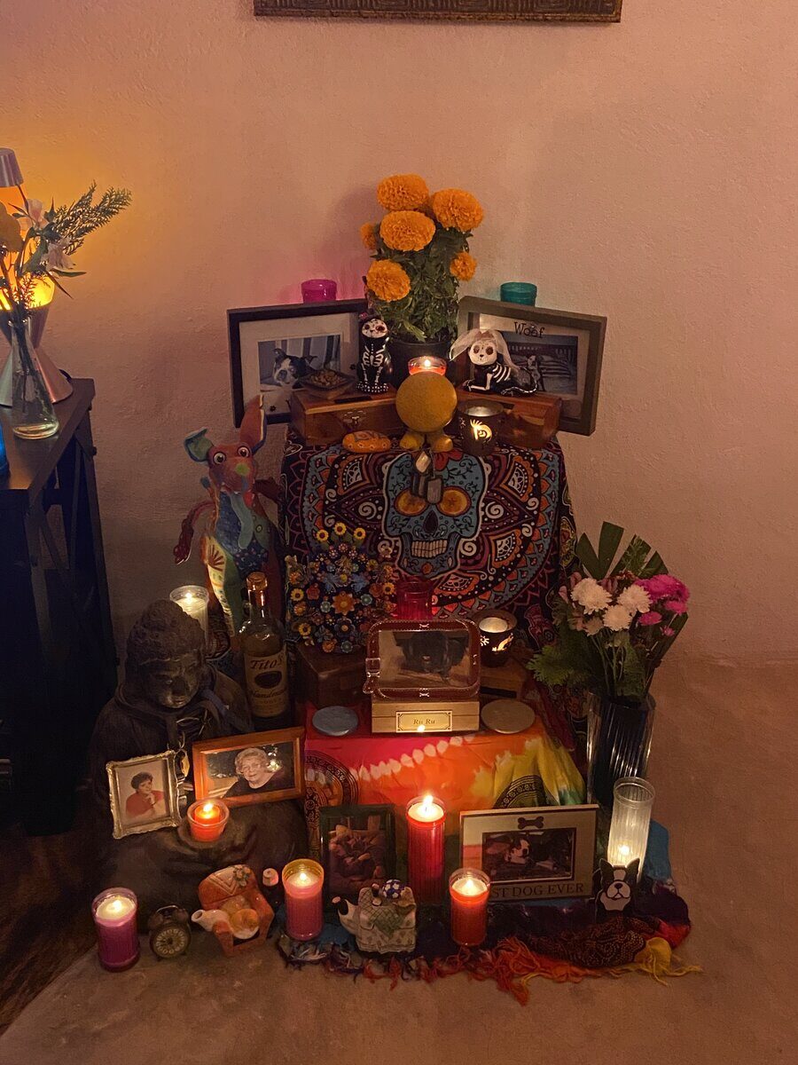 Our ofrenda at home, with framed photos, candles and marigolds
