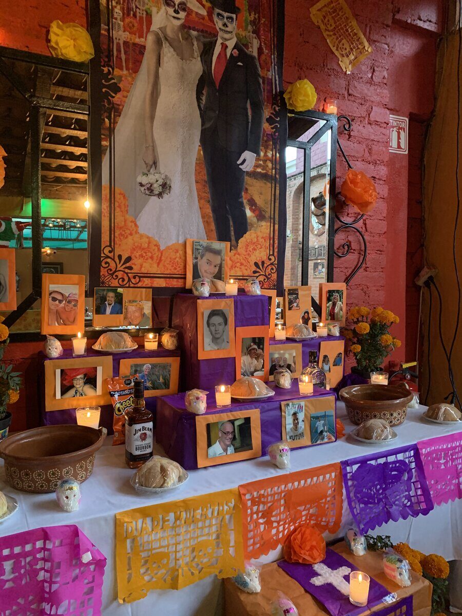 A public ofrenda with framed photos, papel picado, candles and marigolds