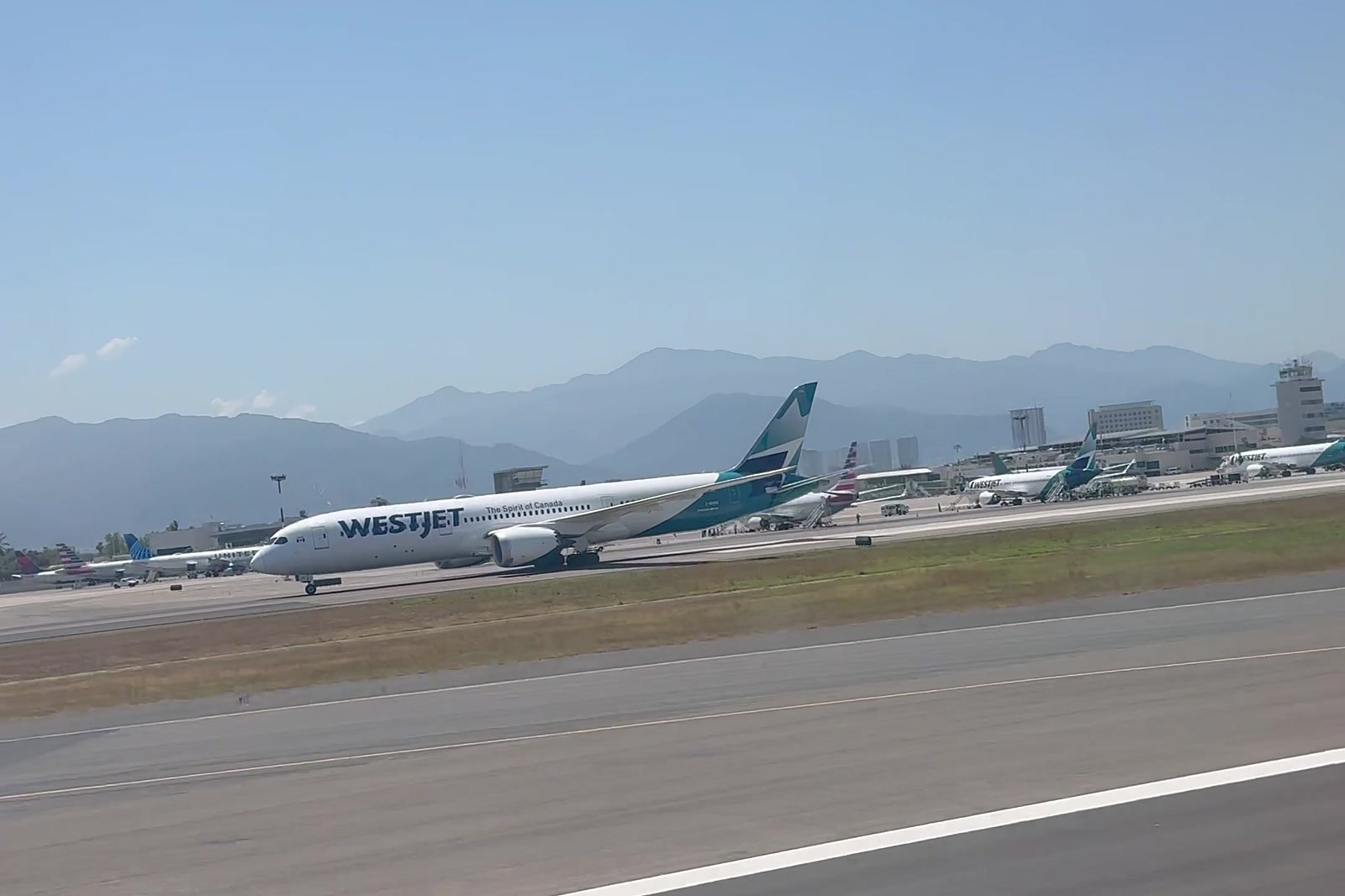 A WestJet Dreamliner on the runway at Puerto Vallarta International Airport, with the Sierra Madre behind