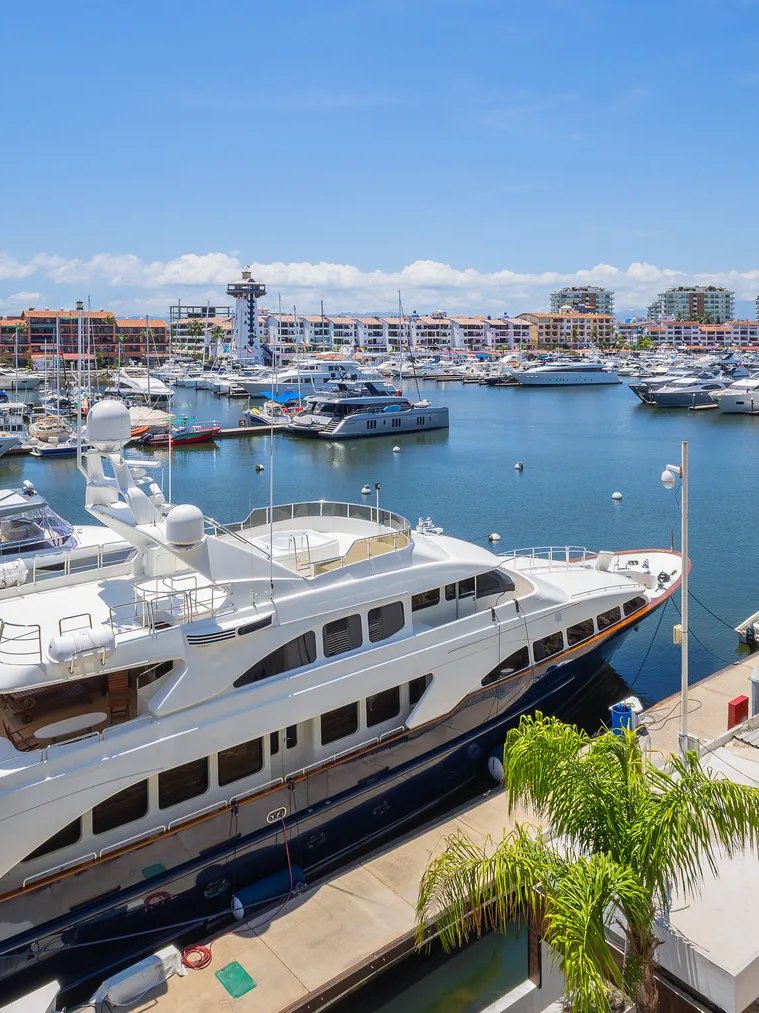 A large white yacht moored in Marina Vallarta under a blue sky