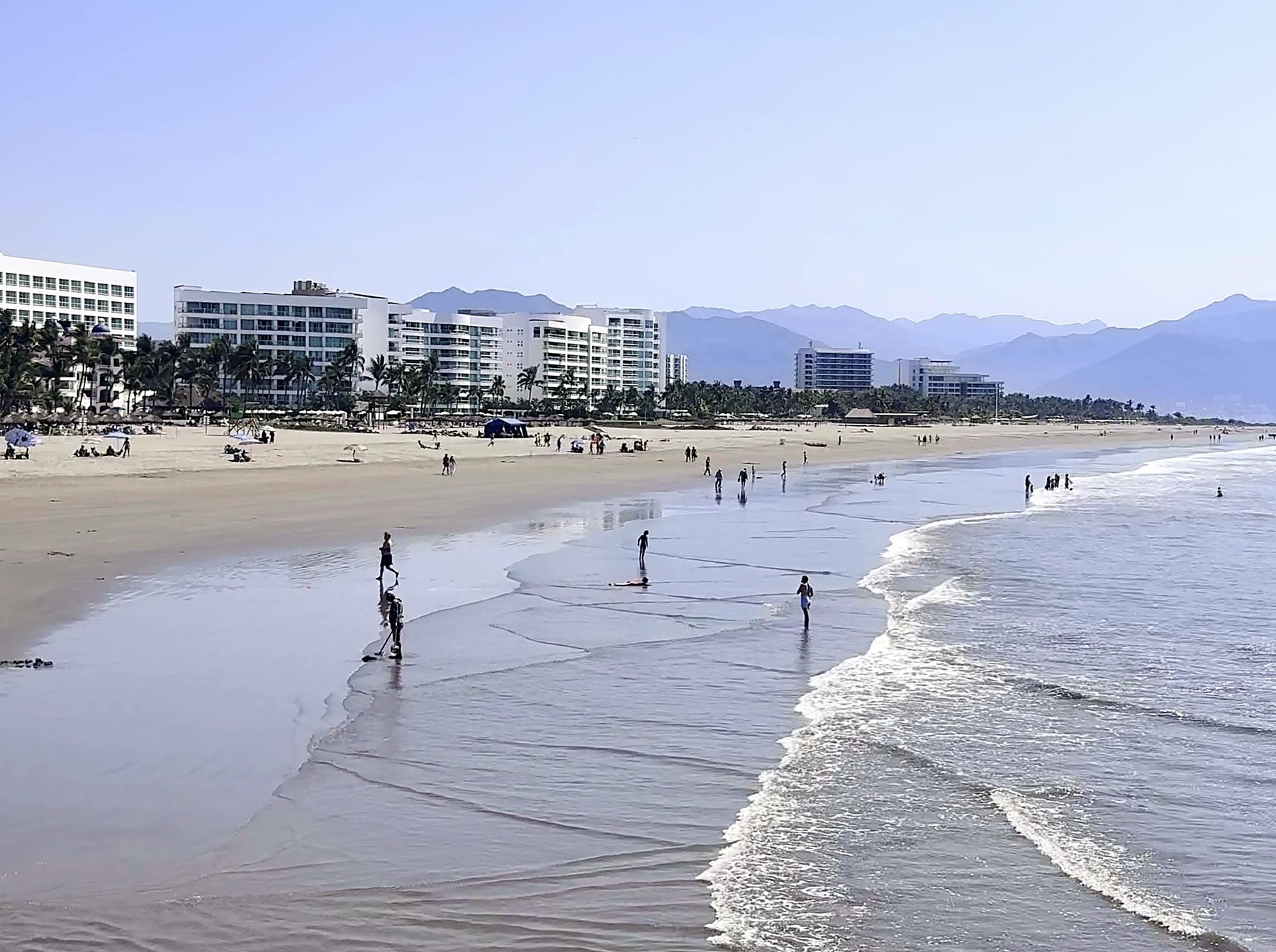 The wide beach at Nuevo Nayarit with resort buildings along the sand and the Sierra Madre behind