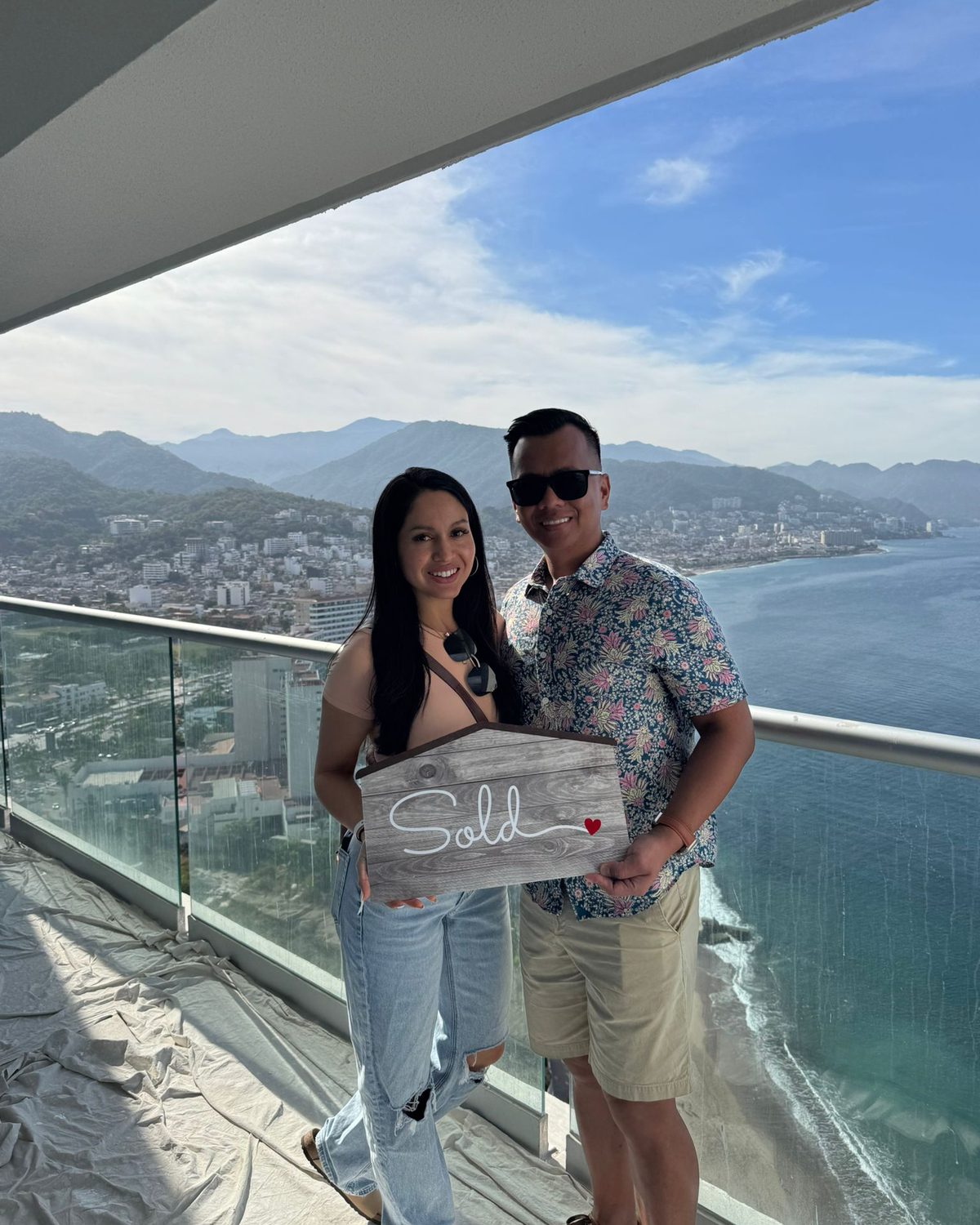 Our clients holding a Sold sign on the terrace of 2701 at Harbor 171, high above the bay