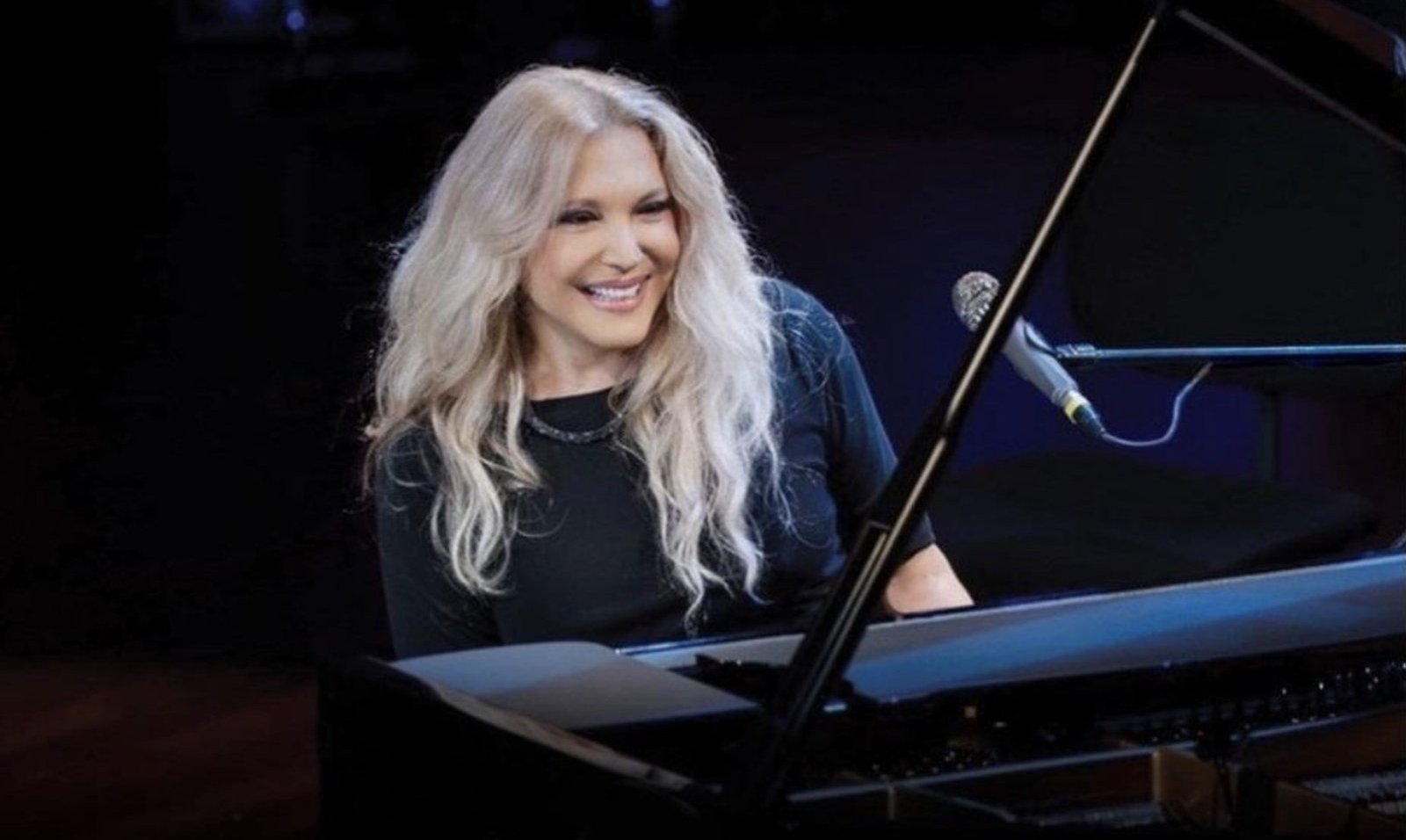 Eliane Elias smiling at a grand piano on stage