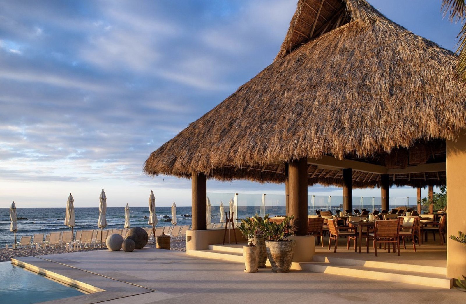 The palapa restaurant and pool deck at Pac&iacute;fico Beach Club, with umbrellas along the beach