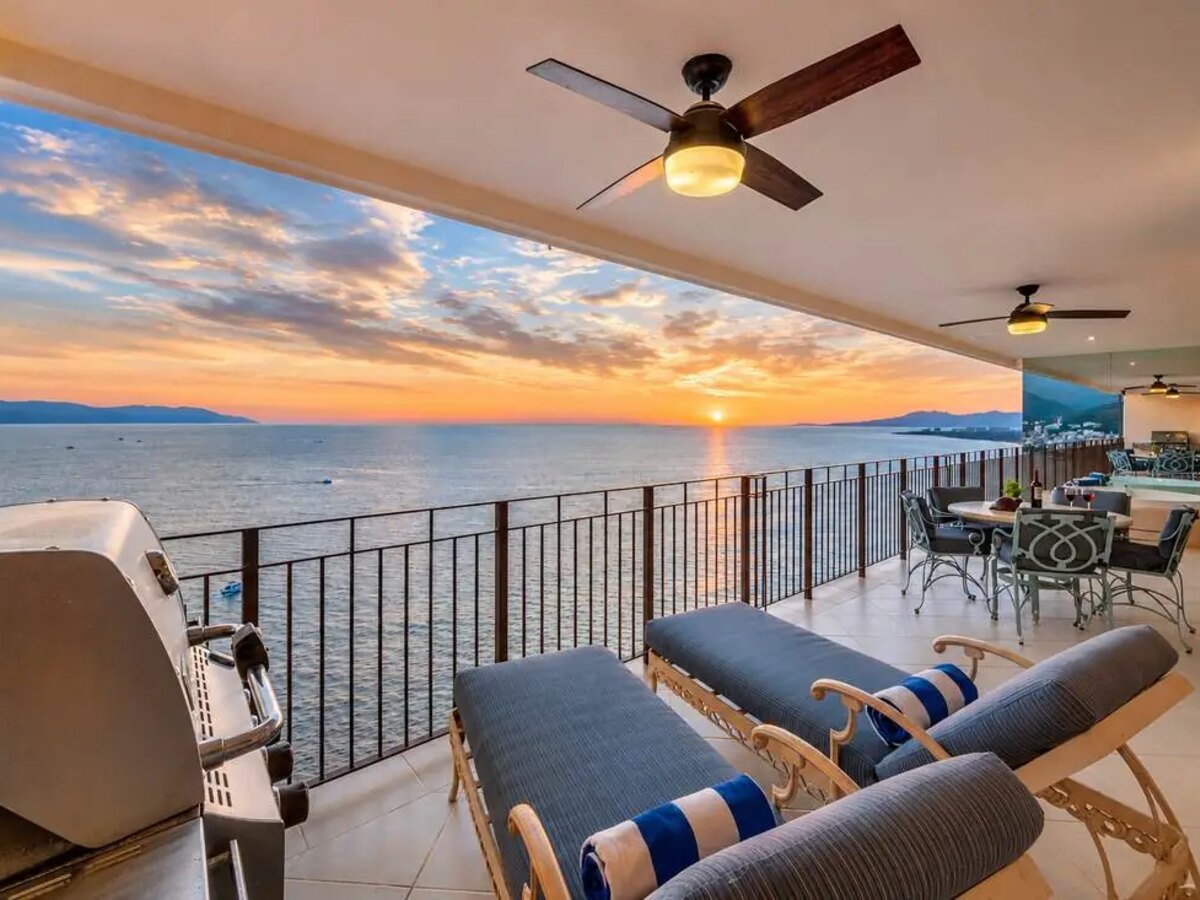 A covered oceanfront terrace at sunset in Puerto Vallarta, loungers facing Banderas Bay