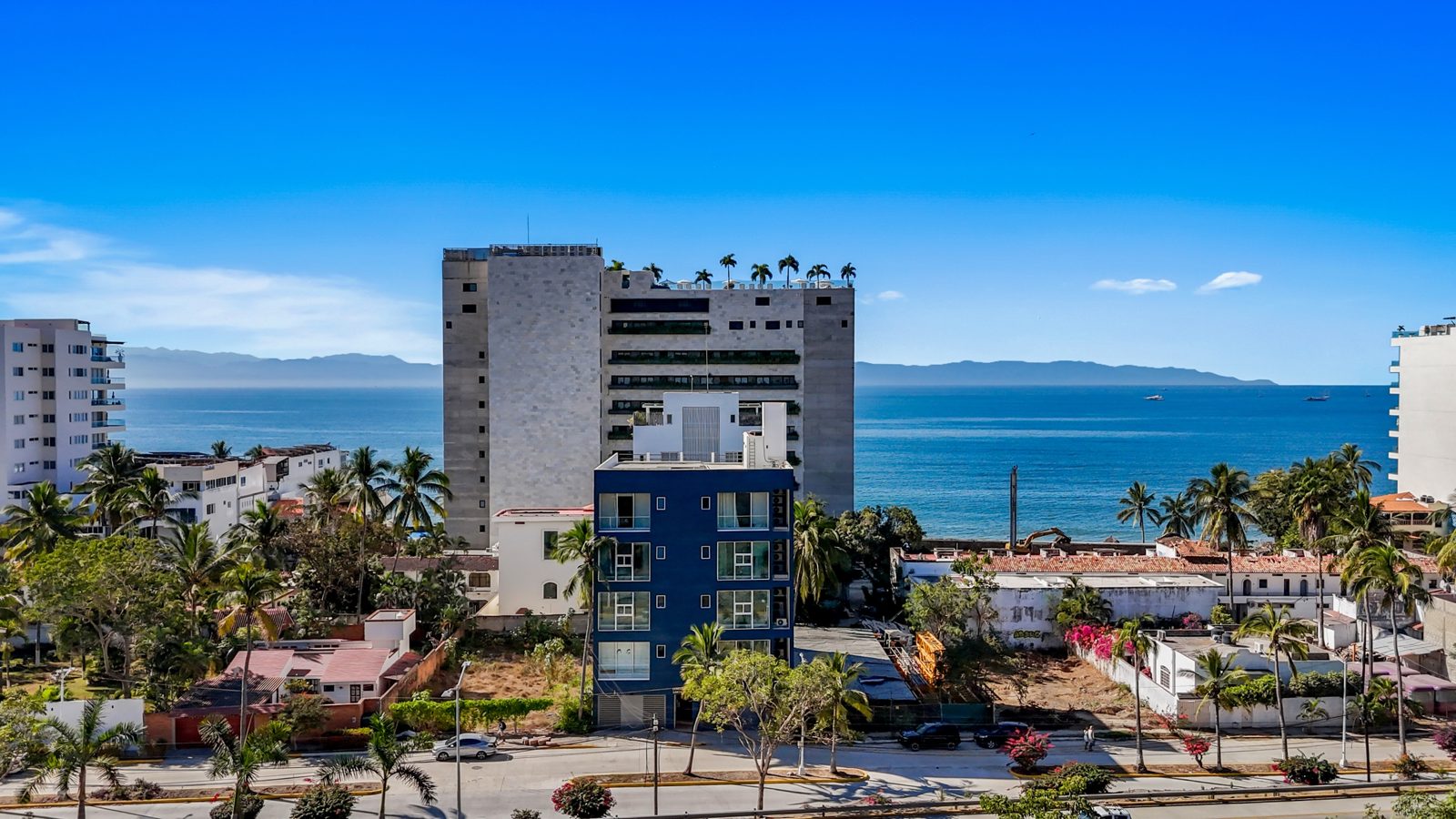 The blue Santa Lucia building in Bucerías with the bay behind it