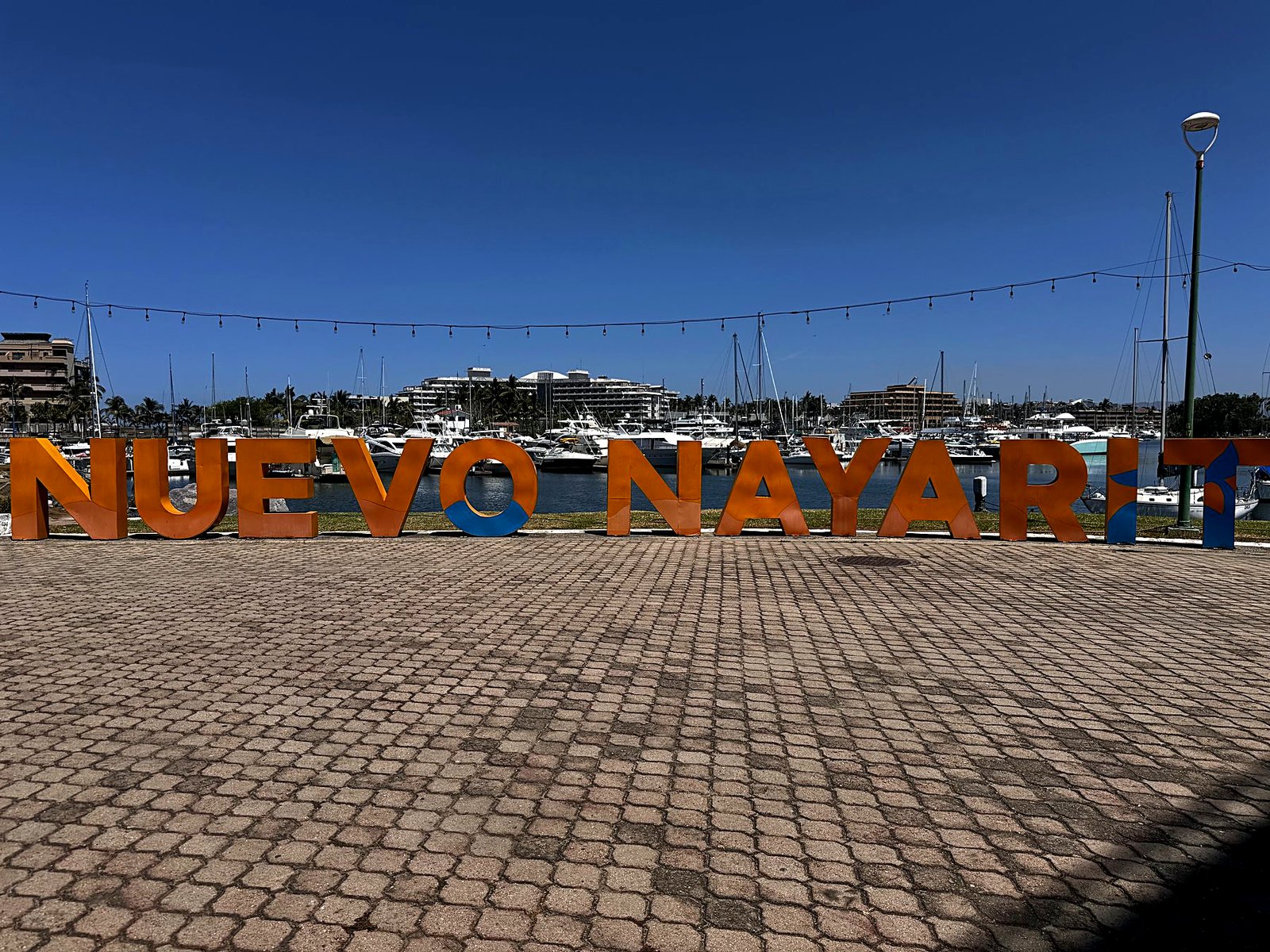 The orange Nuevo Nayarit letters at the marina with yachts and resort buildings behind