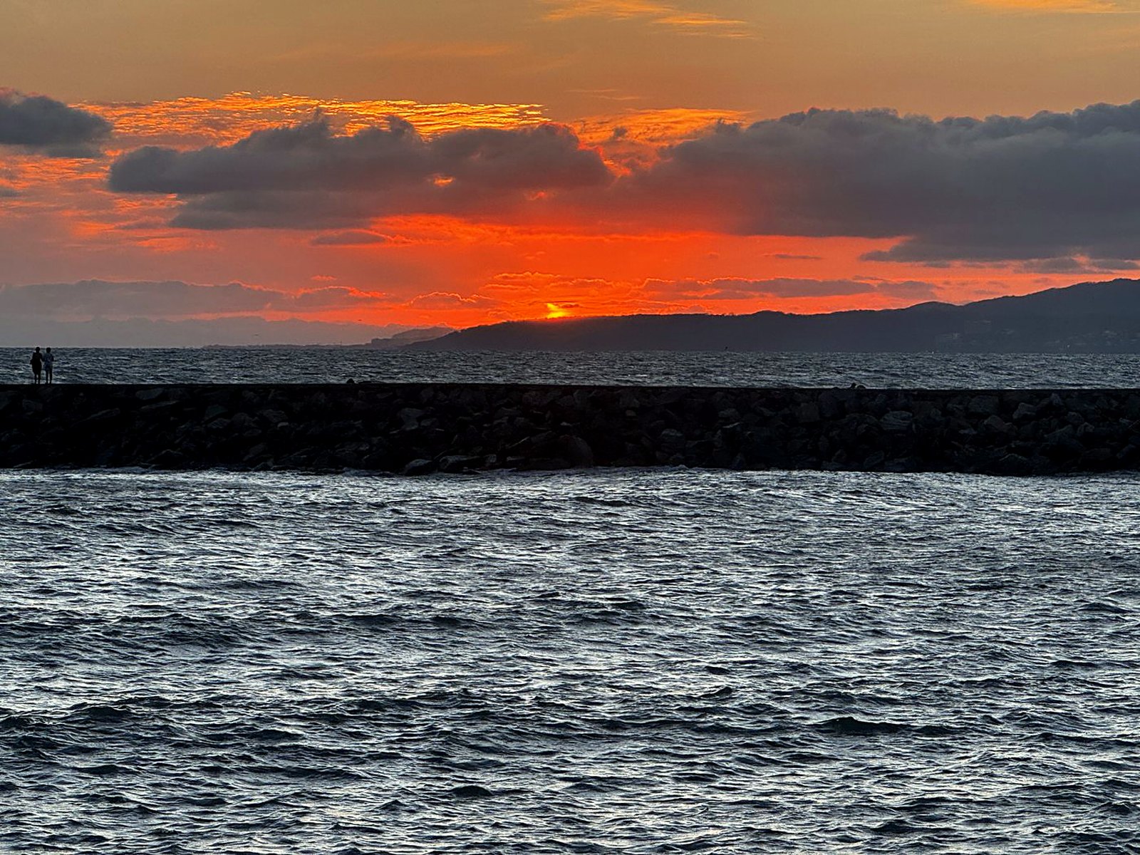 Orange sunset over the breakwater at Nuevo Nayarit with the mountains across the bay