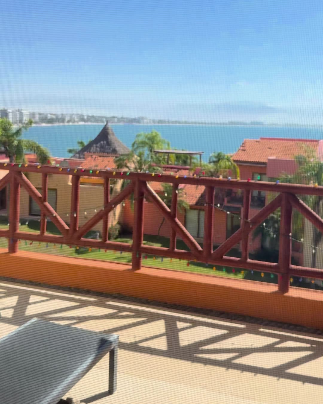 A terrace at Punta Esmeralda looking across tile roofs and palms to the full sweep of Banderas Bay