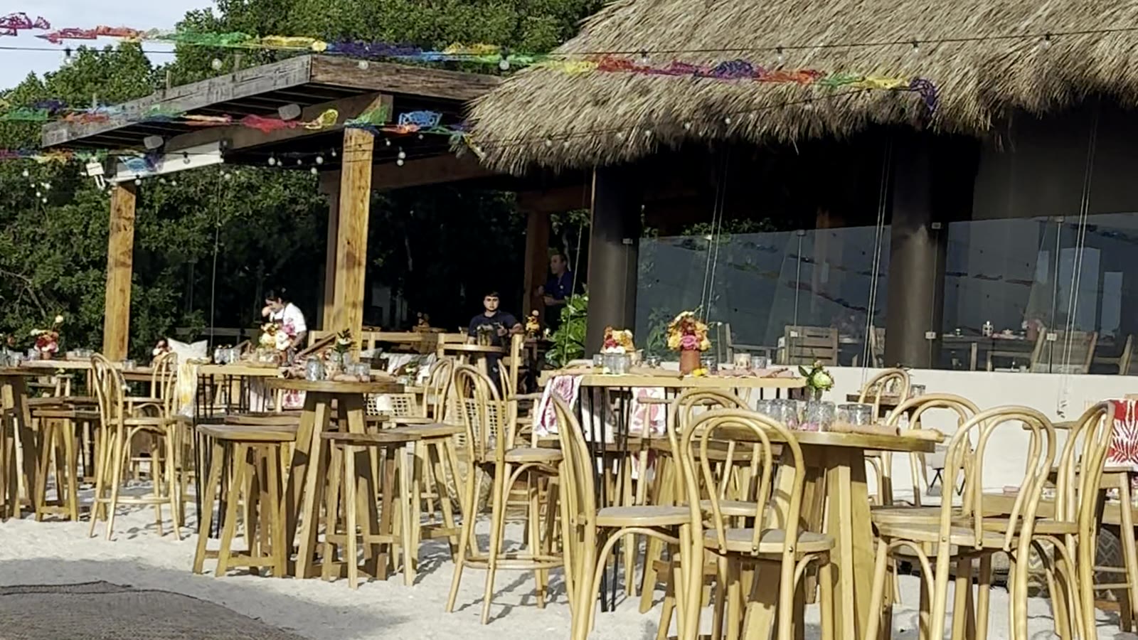 A palapa-roofed beach club restaurant on the sand at Punta Mita, tables set under the thatch
