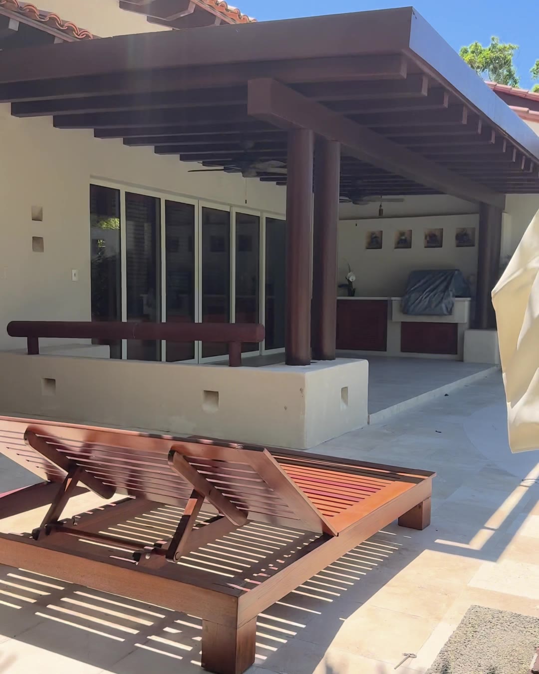 A covered outdoor kitchen and terrace with wooden loungers at a Punta Mita villa