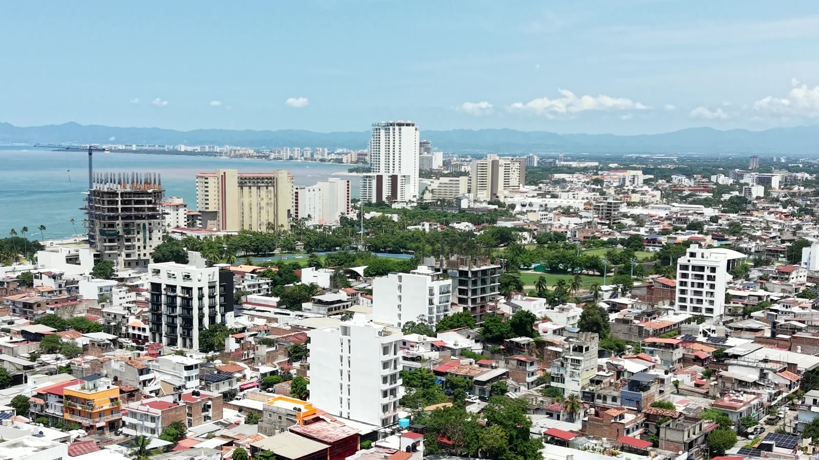 Puerto Vallarta from the air in 2026, towers and cranes along the shoreline with Banderas Bay beyond